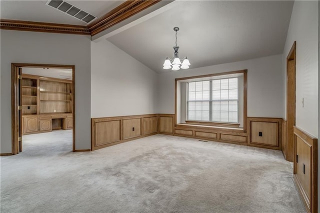 carpeted empty room with an inviting chandelier, crown molding, and vaulted ceiling