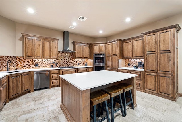 kitchen featuring sink, wall chimney exhaust hood, a center island, a kitchen breakfast bar, and appliances with stainless steel finishes