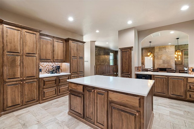 kitchen with dishwasher, a center island, backsplash, hanging light fixtures, and a chandelier