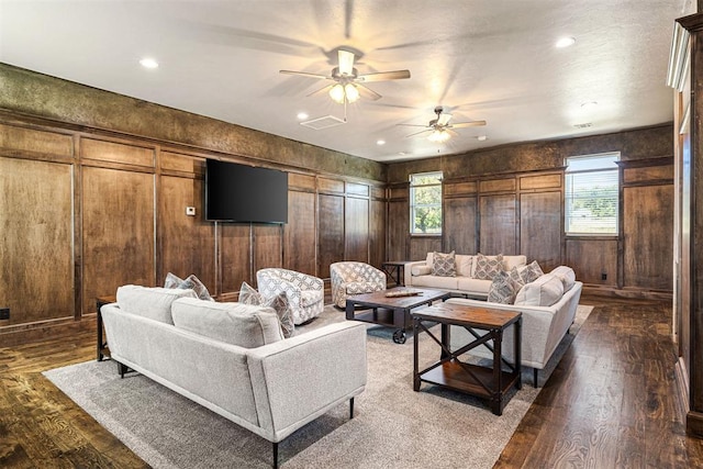 living room with wooden walls, dark hardwood / wood-style floors, ceiling fan, and a healthy amount of sunlight