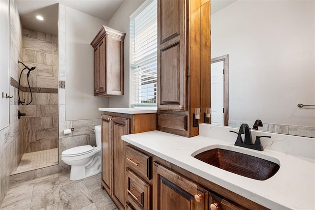 bathroom featuring a tile shower, vanity, toilet, and tile walls