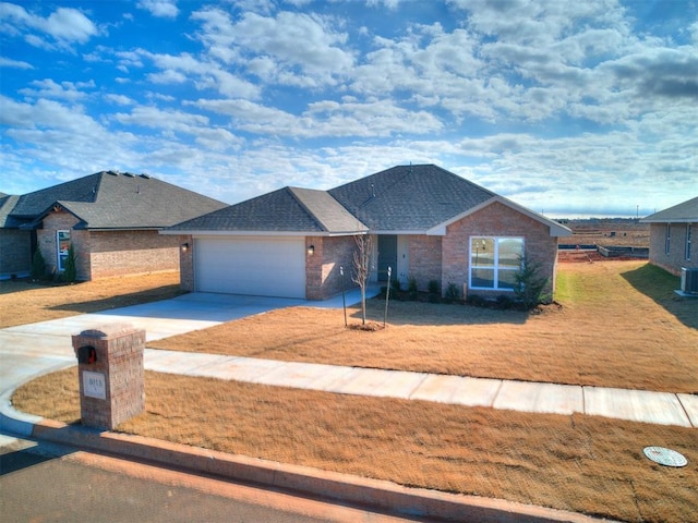 view of front facade featuring a front yard, a garage, and central air condition unit