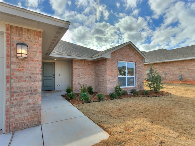 view of exterior entry featuring a lawn