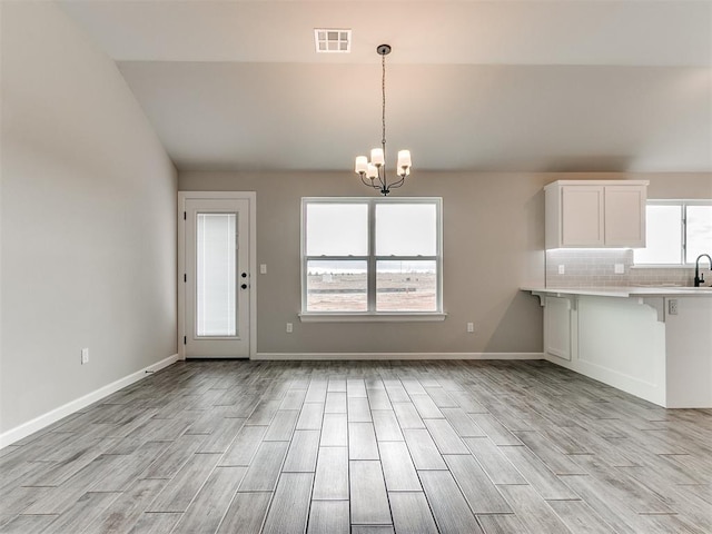 kitchen featuring white cabinets, a kitchen breakfast bar, light wood-type flooring, and an inviting chandelier