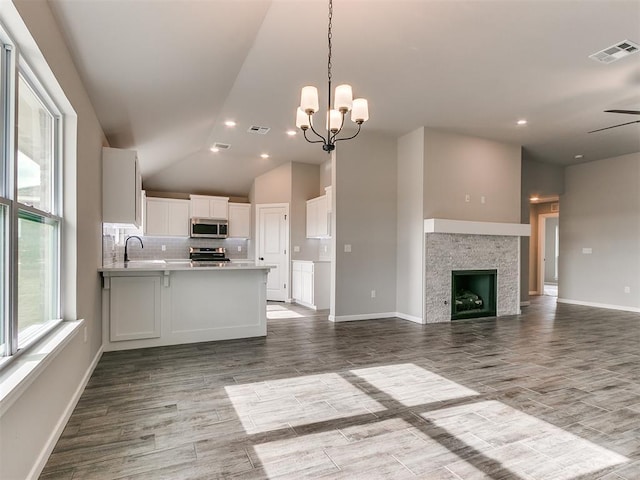 kitchen featuring white cabinetry, stainless steel appliances, kitchen peninsula, wood-type flooring, and ceiling fan with notable chandelier