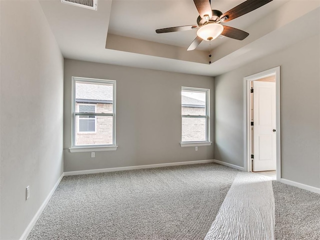 spare room with light colored carpet, a raised ceiling, and ceiling fan