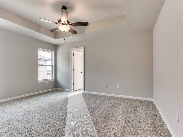 spare room featuring carpet flooring, ceiling fan, and a tray ceiling