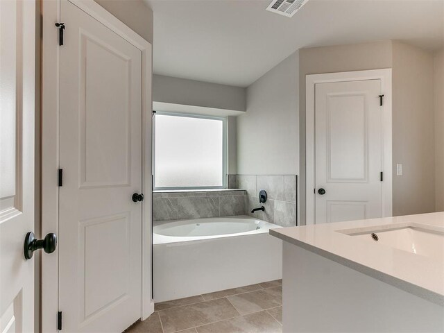 bathroom with a bathing tub, tile patterned flooring, and vanity