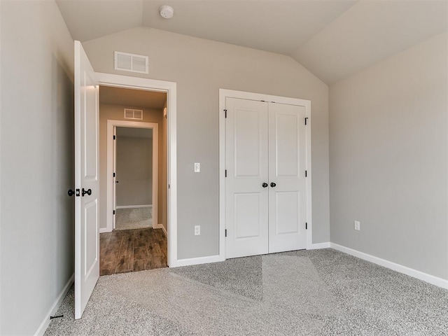 unfurnished bedroom with a closet, carpet floors, and vaulted ceiling