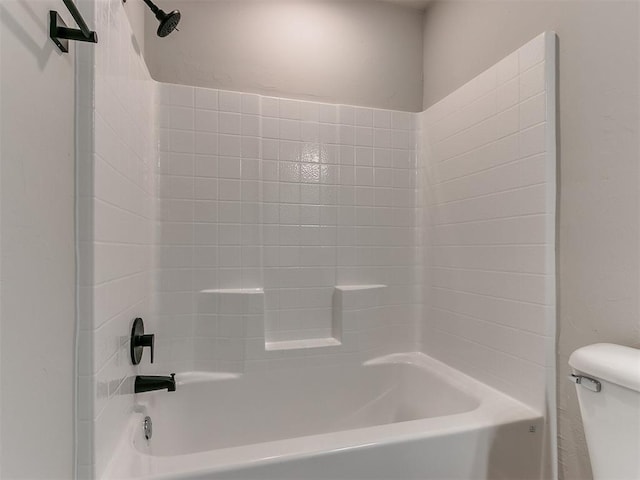 bathroom with tiled shower / bath combo and toilet