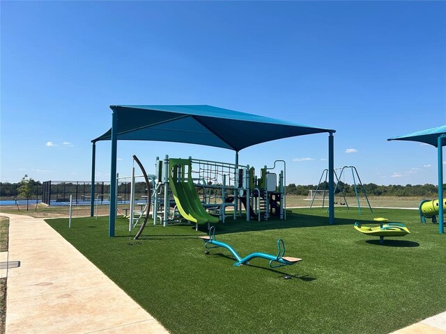 communal playground featuring a lawn and fence