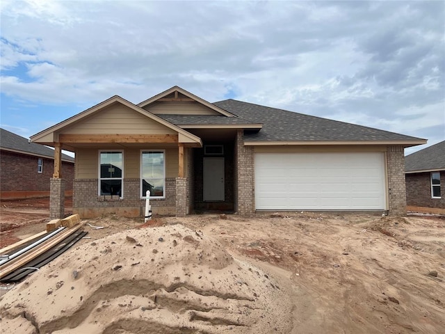 view of front of home with brick siding, an attached garage, and a shingled roof