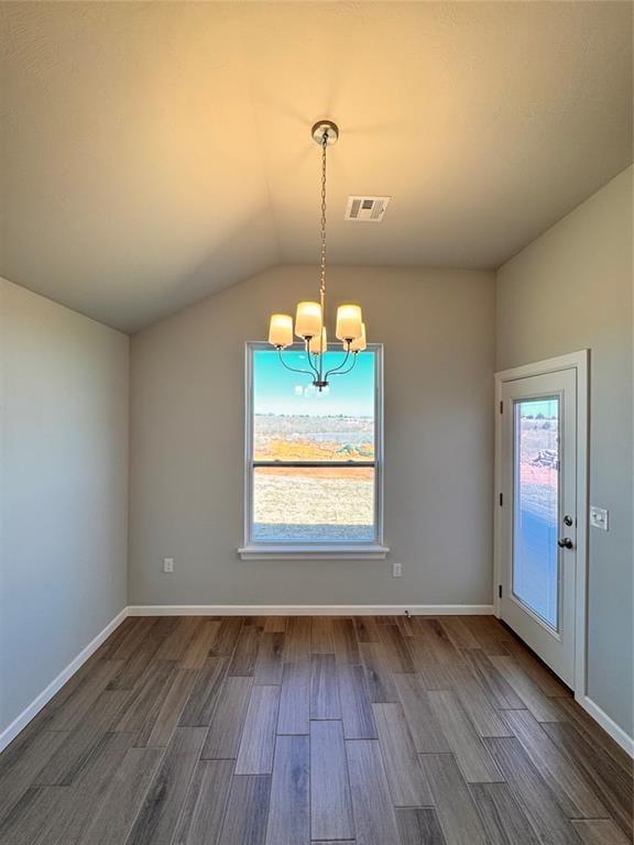 unfurnished dining area with visible vents, dark wood-type flooring, a notable chandelier, lofted ceiling, and baseboards