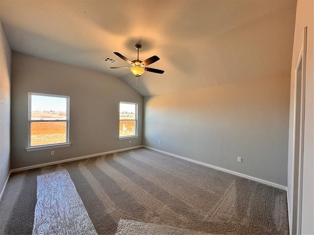 spare room featuring visible vents, lofted ceiling, a ceiling fan, dark carpet, and baseboards