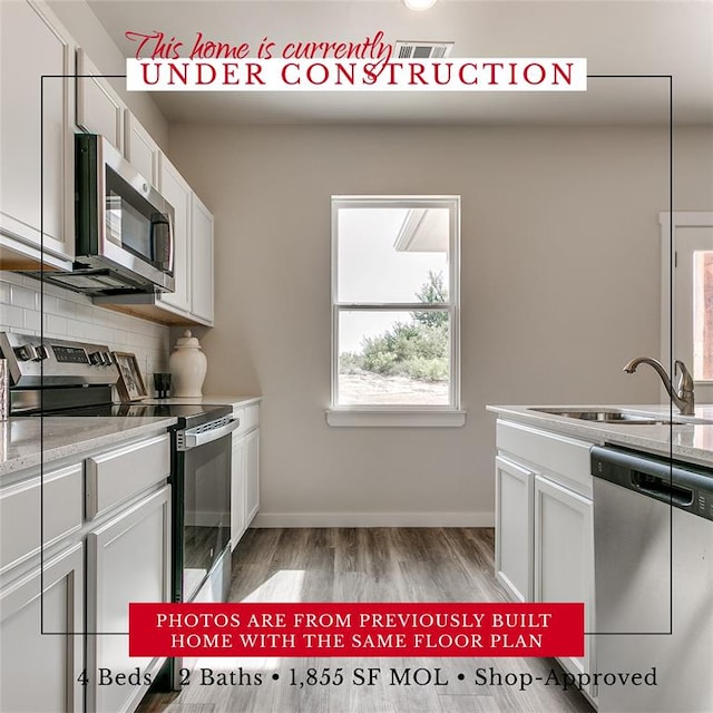 kitchen featuring white cabinets, a sink, stainless steel appliances, and light countertops