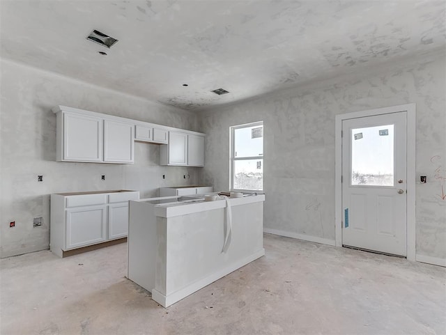 kitchen featuring visible vents, white cabinets, concrete flooring, and a center island