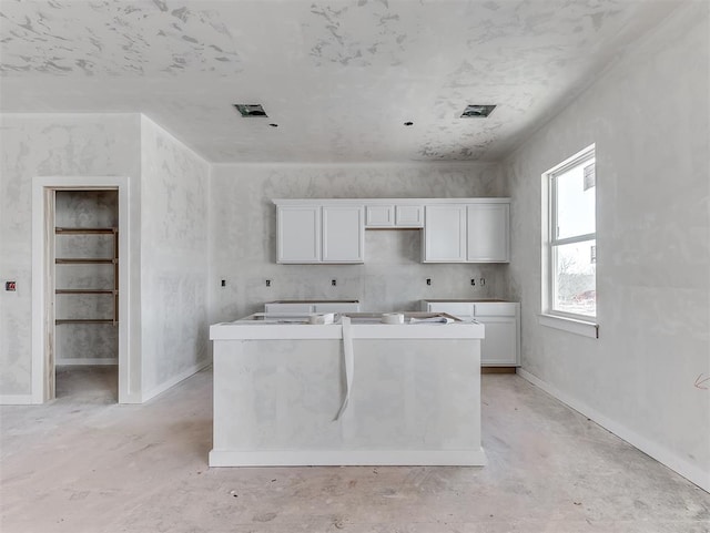 kitchen with white cabinets, visible vents, and unfinished concrete floors