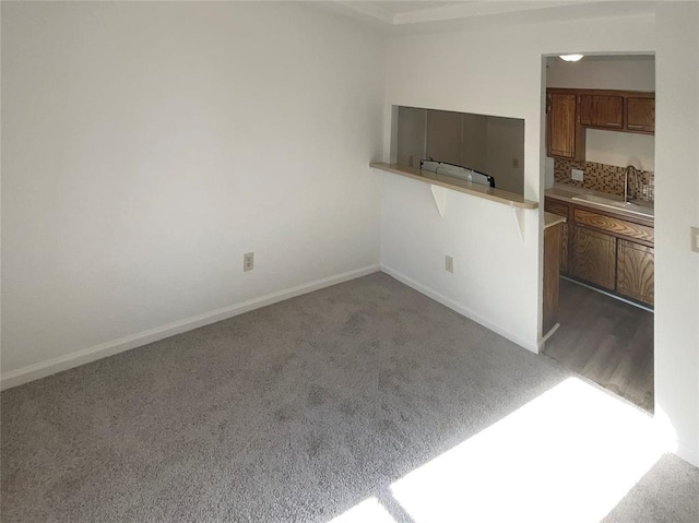 kitchen with dark colored carpet, kitchen peninsula, and sink