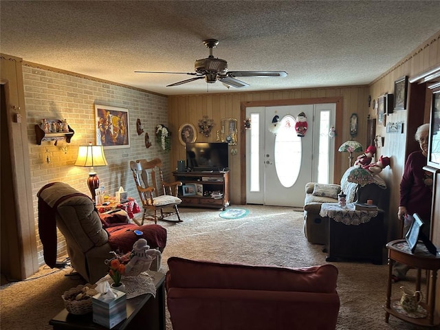 carpeted living room featuring ceiling fan, wooden walls, and a textured ceiling