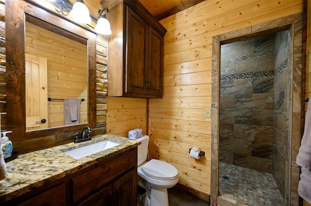 bathroom with wooden walls, toilet, vanity, and tiled shower