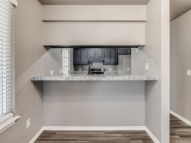 kitchen with stainless steel electric range, dark hardwood / wood-style flooring, light stone counters, and a breakfast bar area