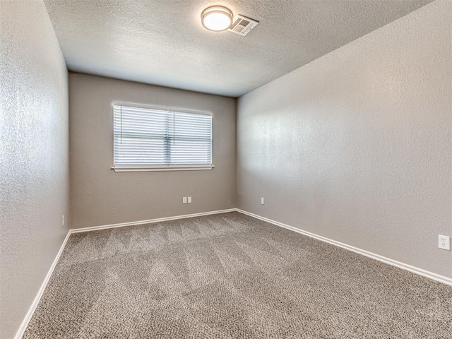 carpeted empty room featuring a textured ceiling