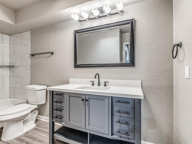 full bathroom with hardwood / wood-style floors, vanity, shower / bathtub combination, and toilet