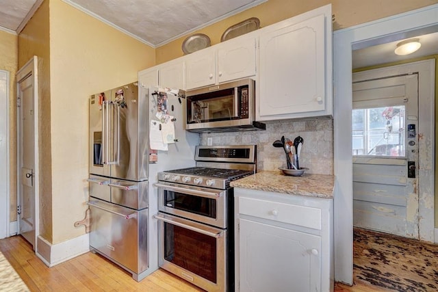 kitchen featuring white cabinetry, light hardwood / wood-style flooring, crown molding, decorative backsplash, and appliances with stainless steel finishes