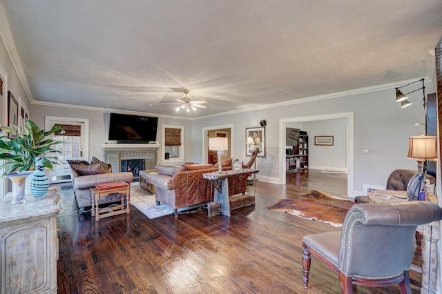 living room featuring a fireplace, dark hardwood / wood-style flooring, ceiling fan, and crown molding