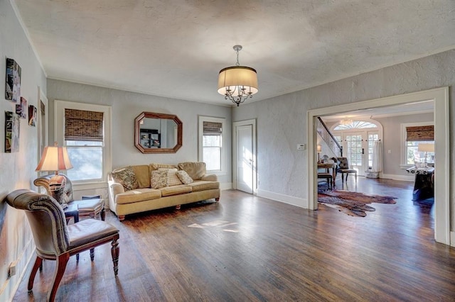 living room featuring plenty of natural light, french doors, dark wood-type flooring, and a chandelier