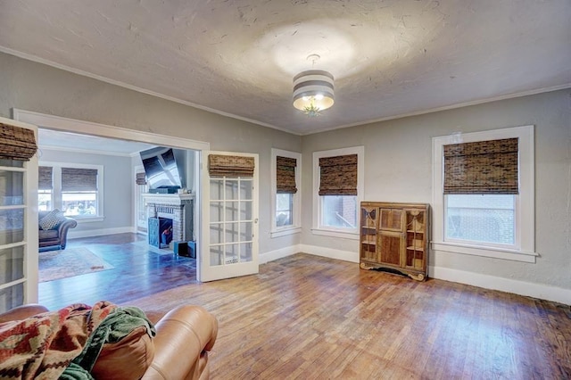 sitting room with a brick fireplace, ornamental molding, and hardwood / wood-style flooring