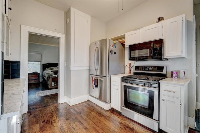 kitchen with light stone countertops, white cabinetry, stainless steel appliances, and dark hardwood / wood-style floors