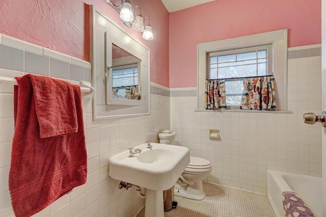 bathroom featuring tile patterned flooring, toilet, tile walls, and a tub