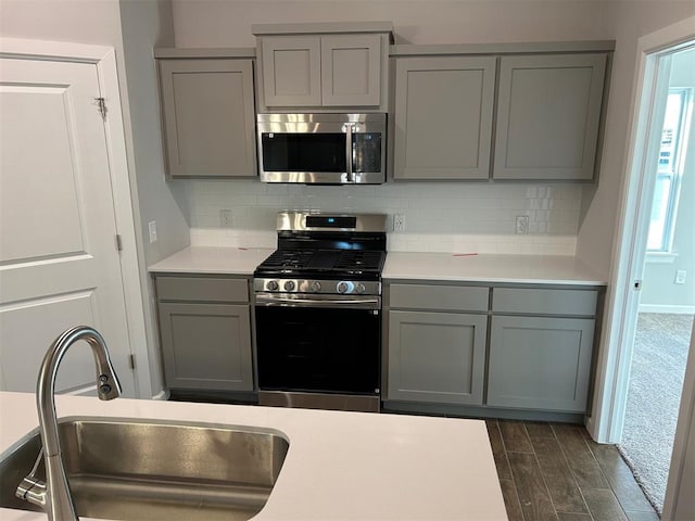 kitchen with gray cabinets, decorative backsplash, sink, and appliances with stainless steel finishes