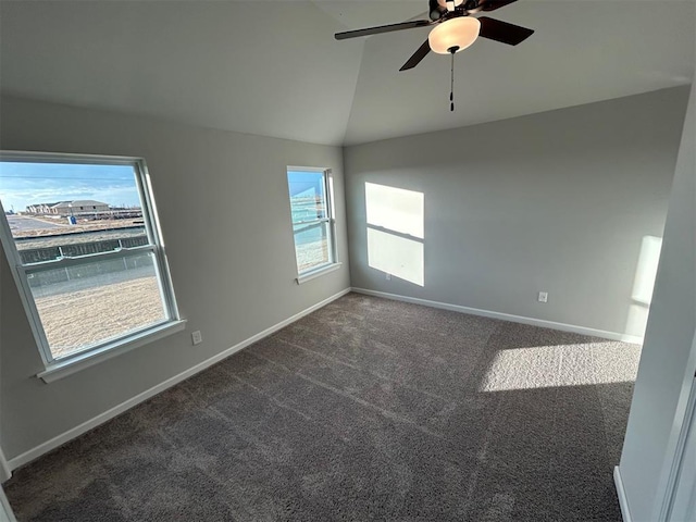 carpeted spare room with ceiling fan, plenty of natural light, and vaulted ceiling