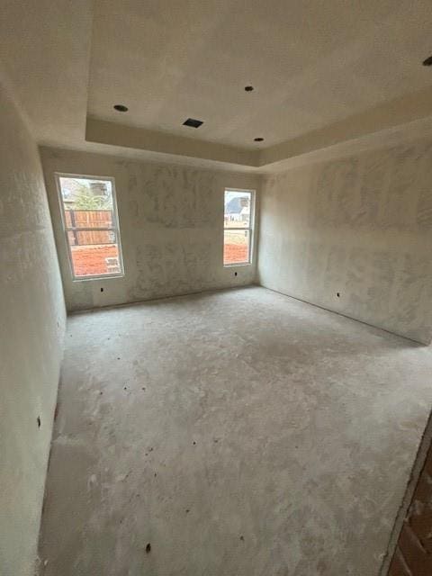 unfurnished room with a wealth of natural light and a tray ceiling