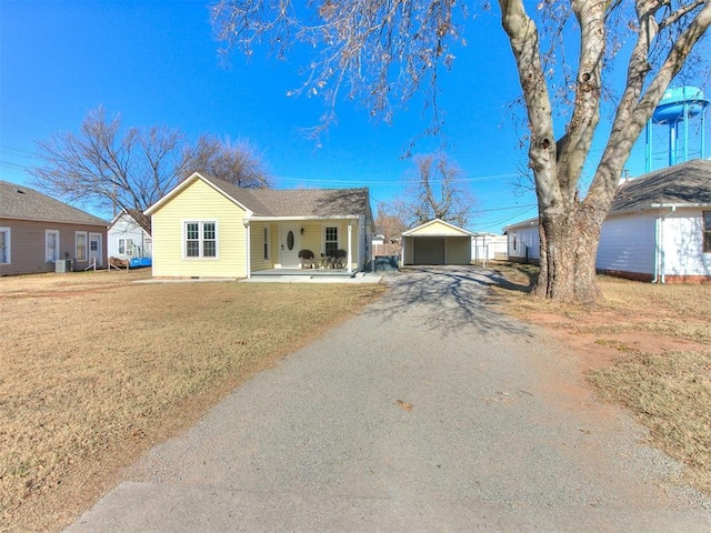 ranch-style home with an outbuilding, a porch, a garage, and a front lawn