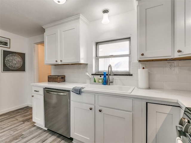 kitchen with appliances with stainless steel finishes, light wood-type flooring, backsplash, sink, and white cabinetry