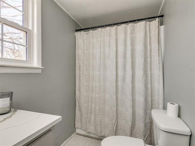 bathroom with toilet, ornamental molding, and walk in shower