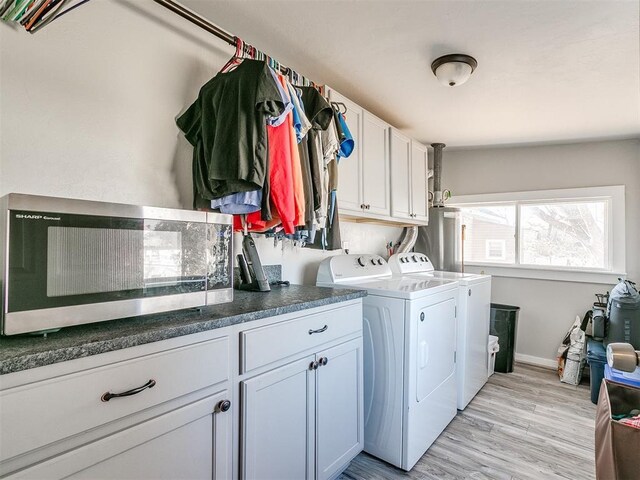 laundry room featuring cabinets, light hardwood / wood-style floors, water heater, and washing machine and clothes dryer