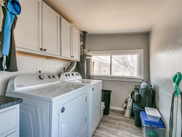 washroom featuring cabinets, washing machine and dryer, gas water heater, and light hardwood / wood-style flooring