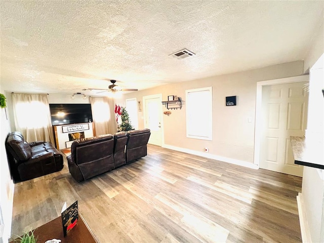 living room featuring wood-type flooring, a textured ceiling, and ceiling fan