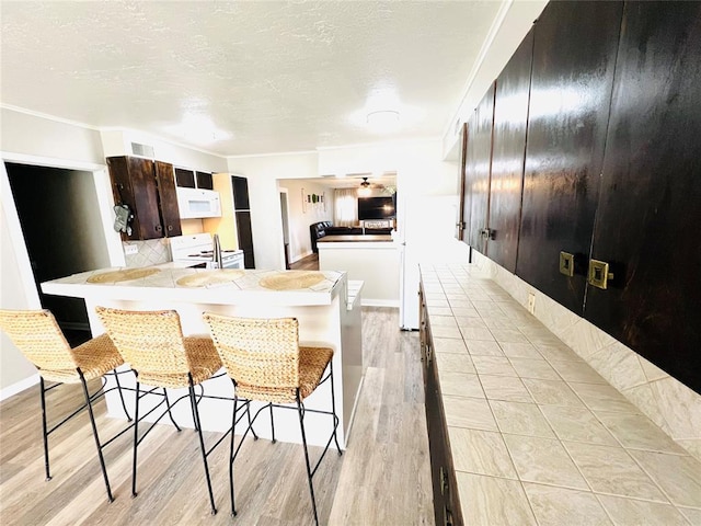 kitchen featuring a kitchen breakfast bar, kitchen peninsula, light hardwood / wood-style flooring, and white appliances