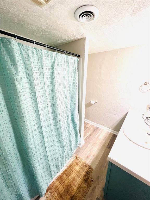 bathroom with hardwood / wood-style floors, vanity, and a textured ceiling