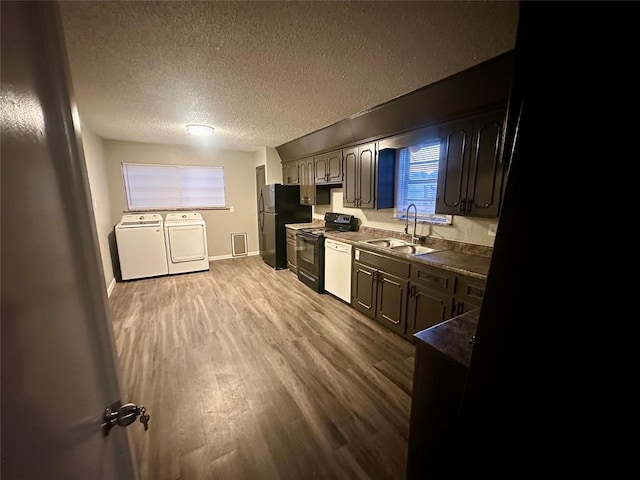 kitchen with washer and dryer, sink, hardwood / wood-style floors, a textured ceiling, and black appliances