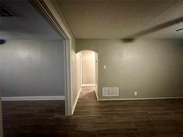 unfurnished room featuring a textured ceiling and dark wood-type flooring