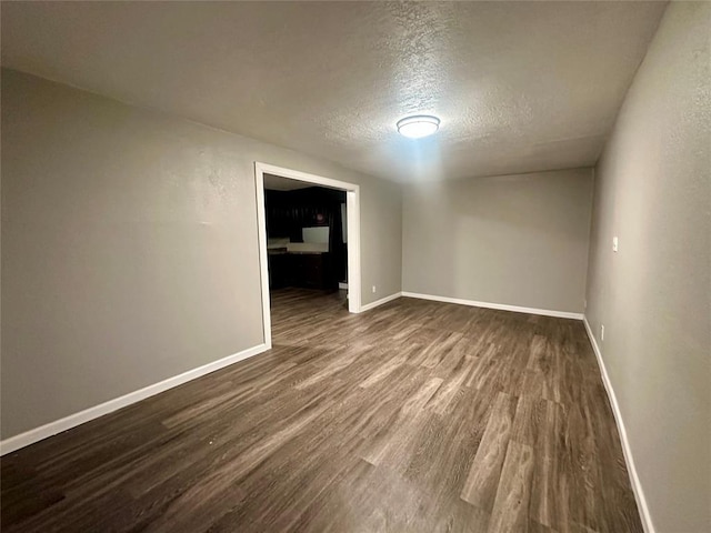 unfurnished room featuring dark wood-type flooring and a textured ceiling