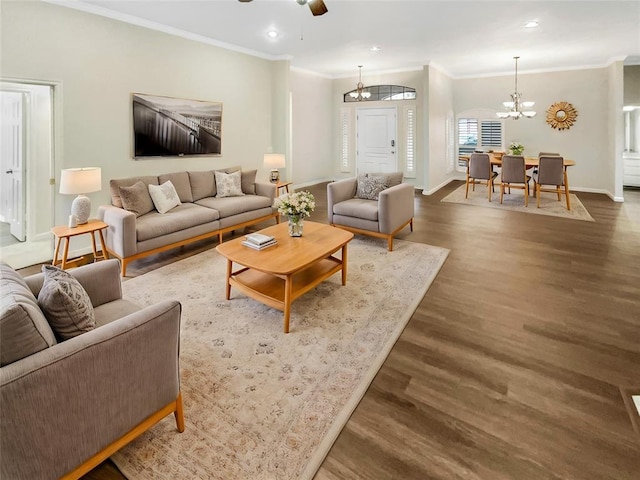 living room featuring dark hardwood / wood-style flooring, ceiling fan with notable chandelier, and ornamental molding