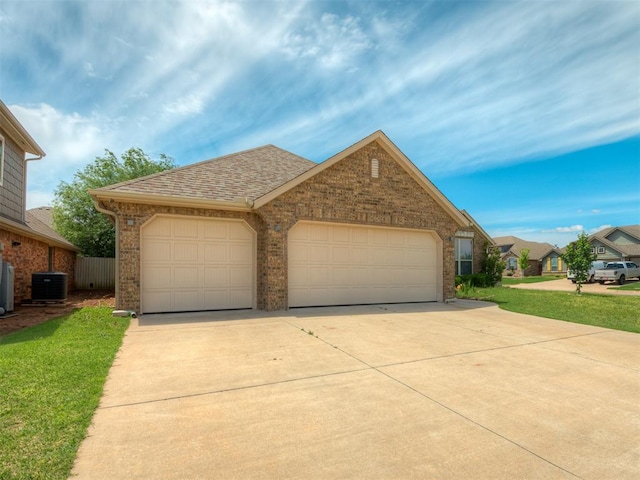 single story home featuring driveway, brick siding, an attached garage, central air condition unit, and a shingled roof