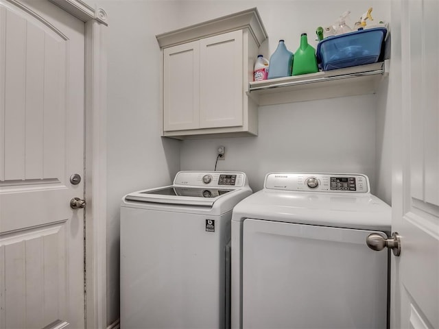 washroom featuring washing machine and dryer and cabinet space
